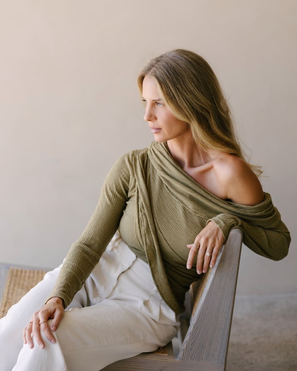 Elle seated in a sculptural chair, looking away