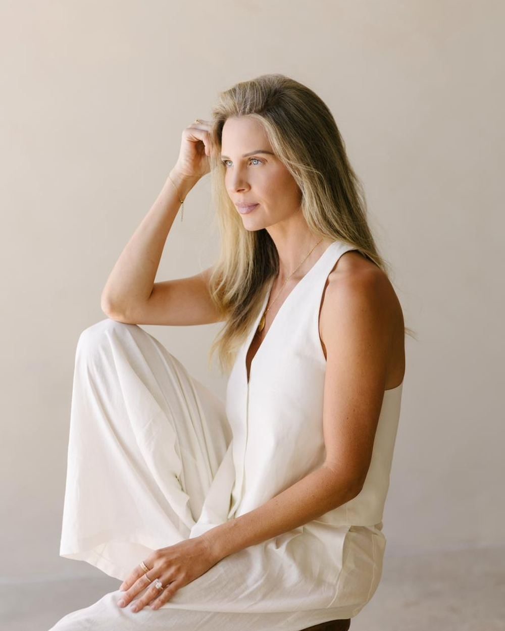 Elle seated on a wooden stool in soft light